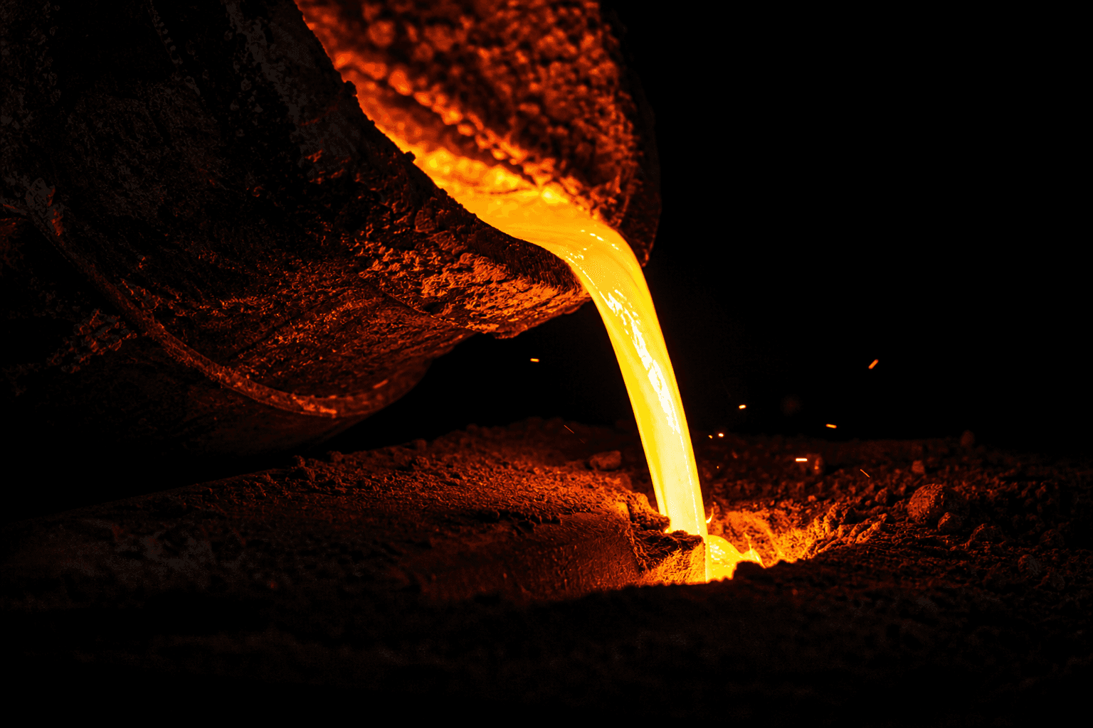 Molten iron pouring from a foundry ladle into a sand mould
